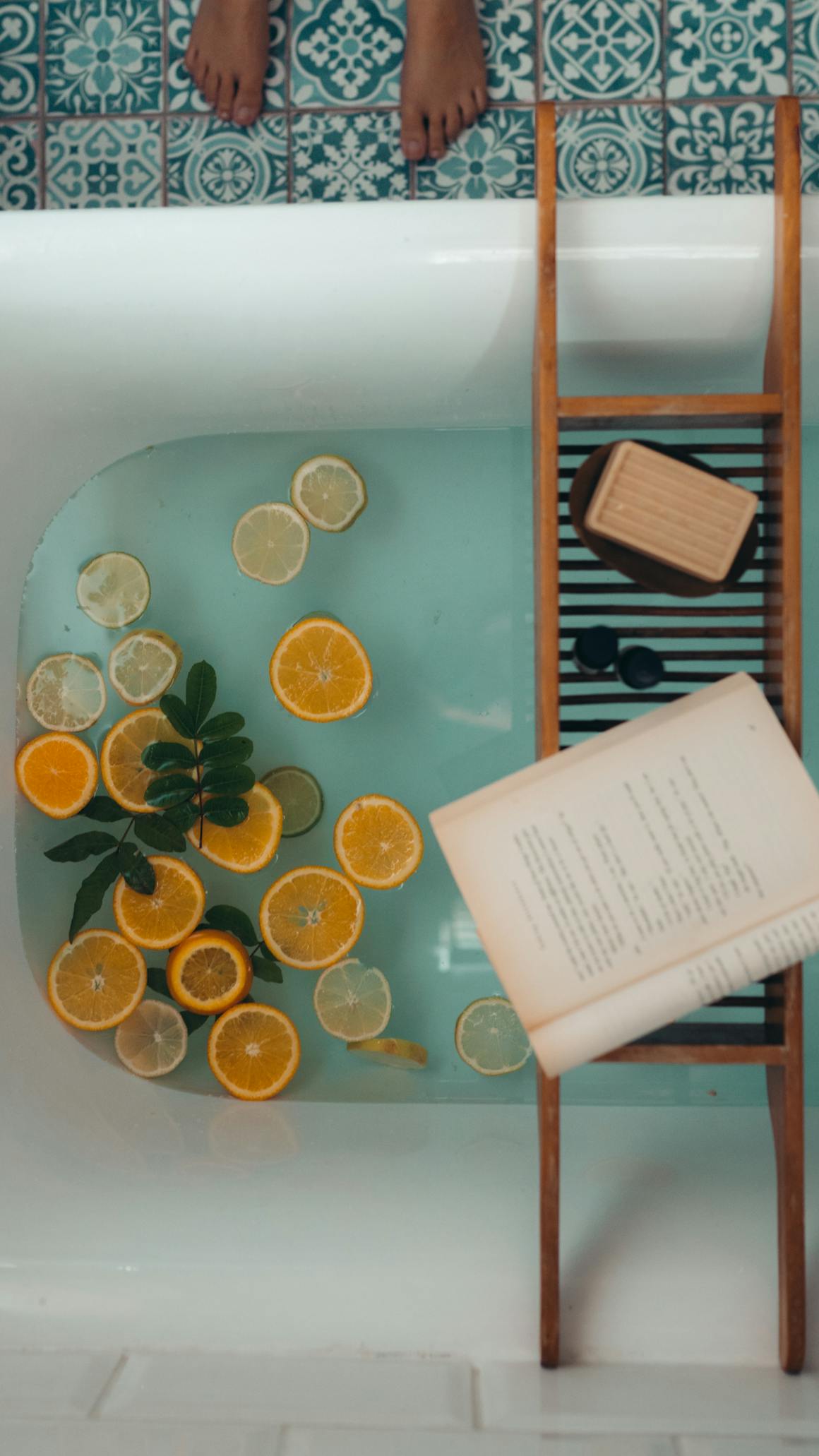 A serene bath setup with citrus fruits, a book, and a bar of soap for ultimate relaxation.